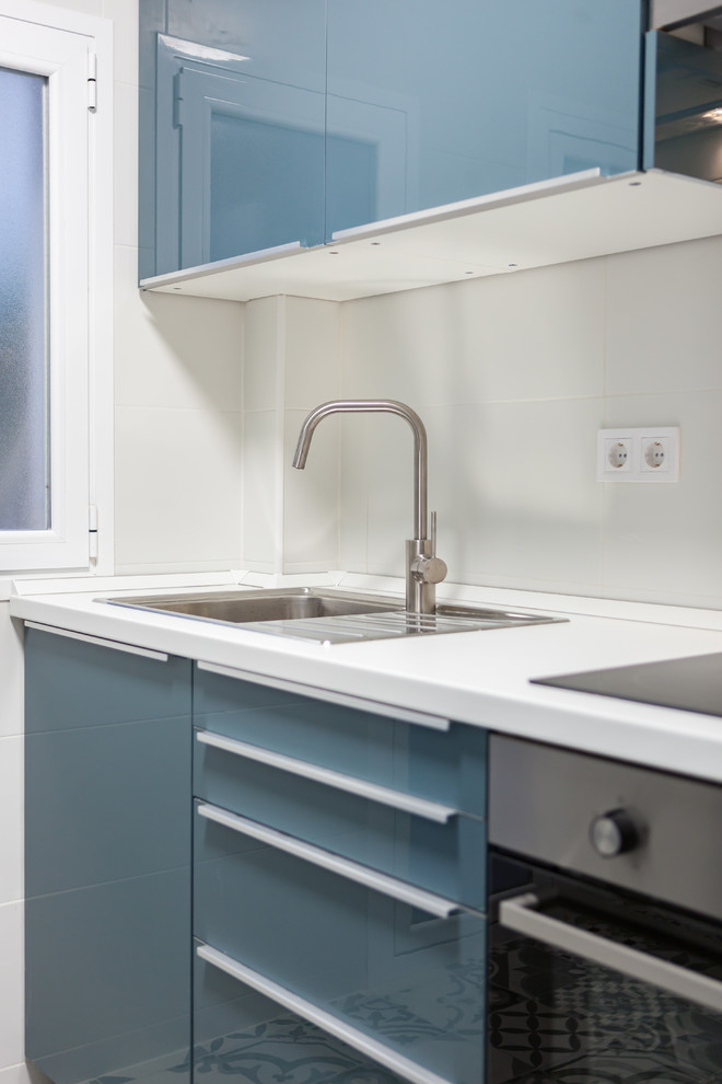 Medium sized contemporary enclosed kitchen in Madrid with a single-bowl sink, flat-panel cabinets, grey cabinets, white splashback, ceramic splashback, integrated appliances, ceramic flooring and grey floors.
