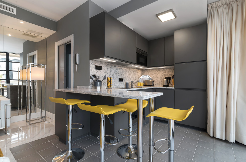 Modern inredning av ett litet grå grått u-kök, med en undermonterad diskho, släta luckor, grå skåp, grått stänkskydd, integrerade vitvaror, klinkergolv i porslin, en halv köksö och grått golv