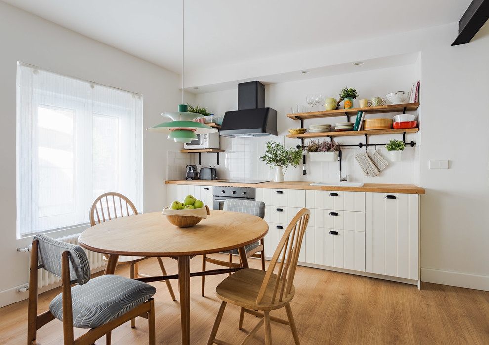 Modelo de cocina comedor nórdica con fregadero encastrado, armarios abiertos, encimera de madera, salpicadero blanco y suelo de madera en tonos medios