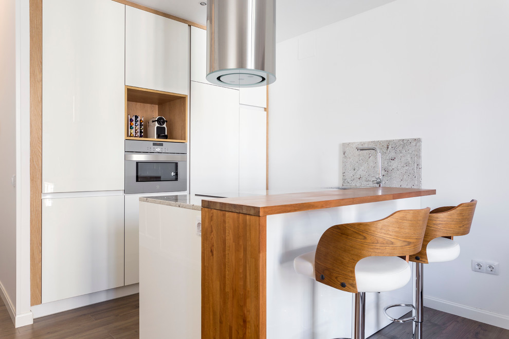 Inspiration for a small contemporary single-wall open concept kitchen remodel in Madrid with flat-panel cabinets, white cabinets, granite countertops and a peninsula