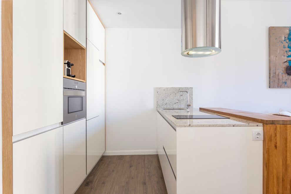 Modelo de cocina lineal actual pequeña abierta con armarios con paneles lisos, puertas de armario blancas, encimera de granito y península