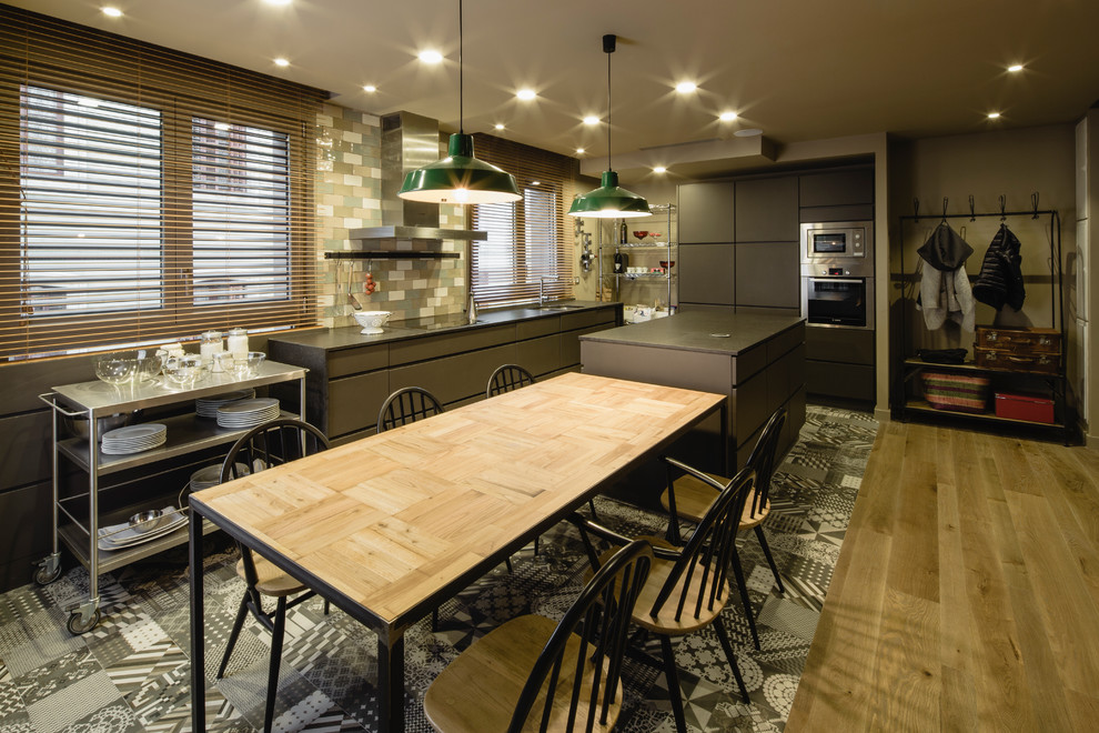 This is an example of a large urban l-shaped kitchen/diner in Barcelona with flat-panel cabinets, grey cabinets, multi-coloured splashback, ceramic splashback, stainless steel appliances, ceramic flooring and an island.