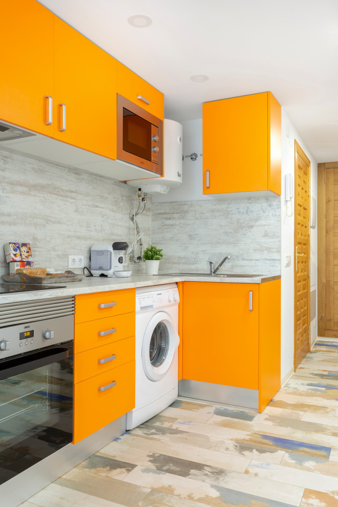 Inredning av ett modernt grå grått l-kök, med en nedsänkt diskho, släta luckor, orange skåp, grått stänkskydd, rostfria vitvaror, målat trägolv och flerfärgat golv