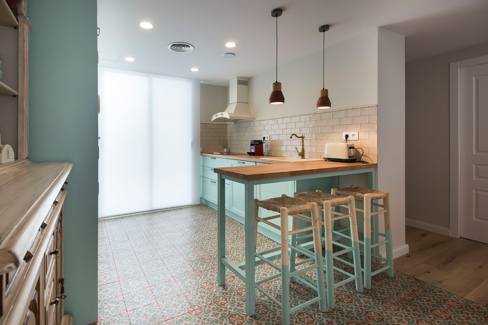 Идея дизайна: угловая кухня среднего размера в средиземноморском стиле с обеденным столом, бирюзовыми фасадами, деревянной столешницей, полом из керамической плитки и полуостровом