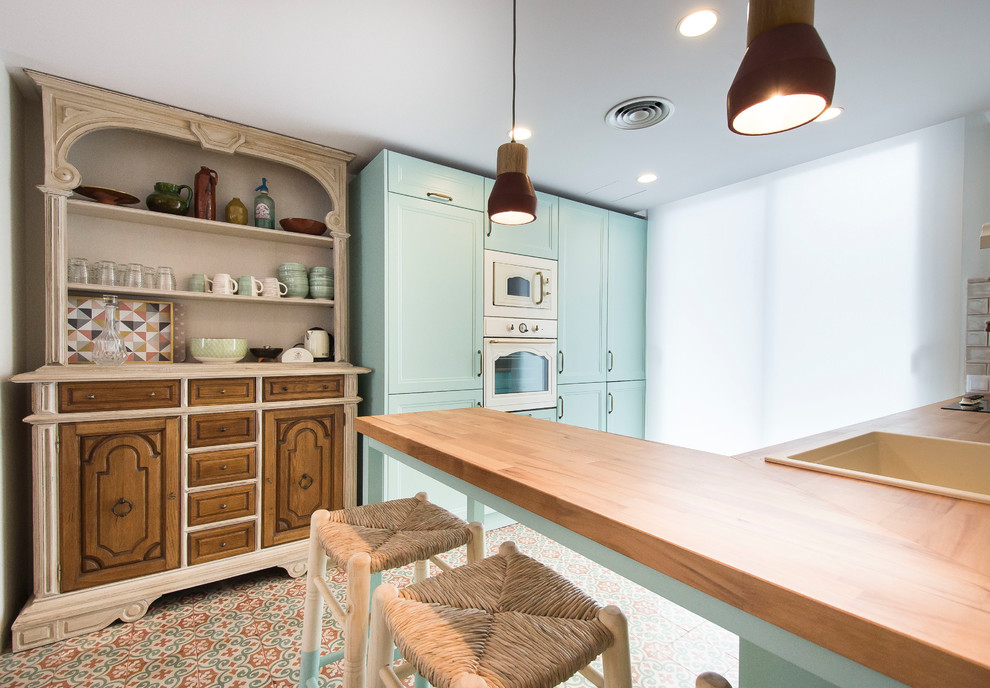 Mid-sized tuscan l-shaped ceramic tile eat-in kitchen photo in Other with turquoise cabinets, wood countertops and a peninsula
