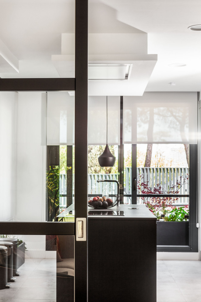 Photo of a contemporary single-wall enclosed kitchen in Madrid with a built-in sink, recessed-panel cabinets, white cabinets, engineered stone countertops, integrated appliances, limestone flooring, an island, grey floors and black worktops.