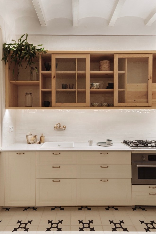 Design ideas for a classic single-wall kitchen in Barcelona with a built-in sink, white splashback, stainless steel appliances, white worktops, raised-panel cabinets, beige cabinets, ceramic splashback and multi-coloured floors.
