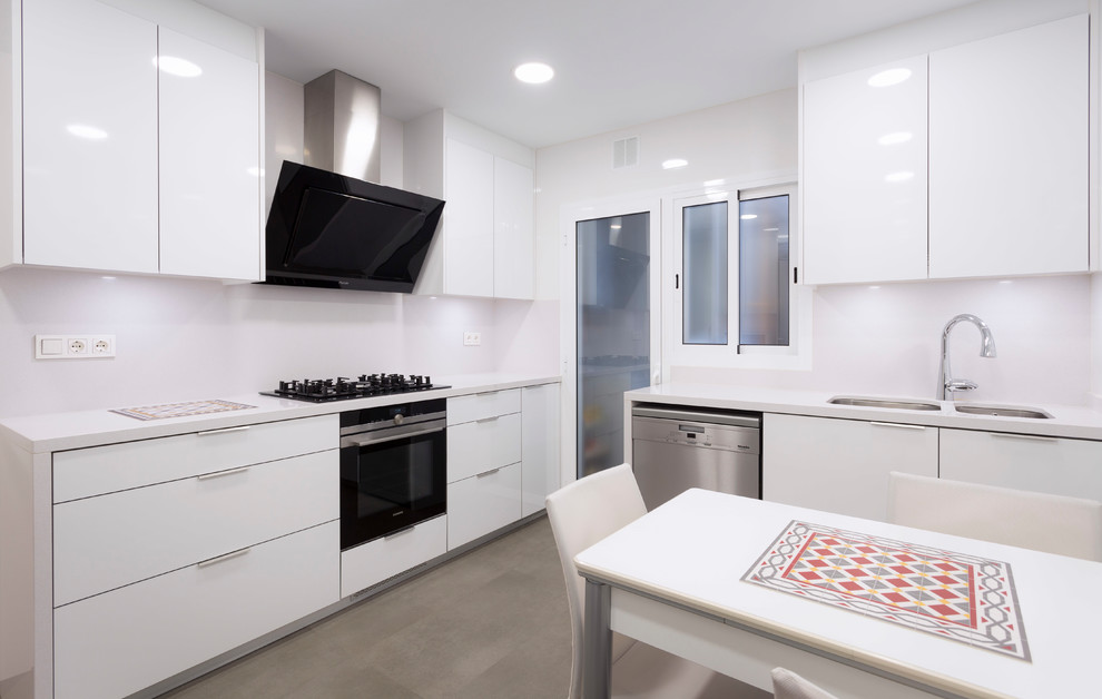 Design ideas for a medium sized contemporary u-shaped enclosed kitchen in Barcelona with a double-bowl sink, white cabinets, white splashback, stainless steel appliances, ceramic flooring, no island, beige floors and white worktops.
