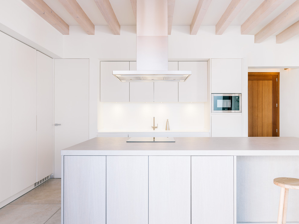 Cette photo montre une cuisine linéaire méditerranéenne de taille moyenne avec un placard à porte plane, des portes de placard blanches et îlot.