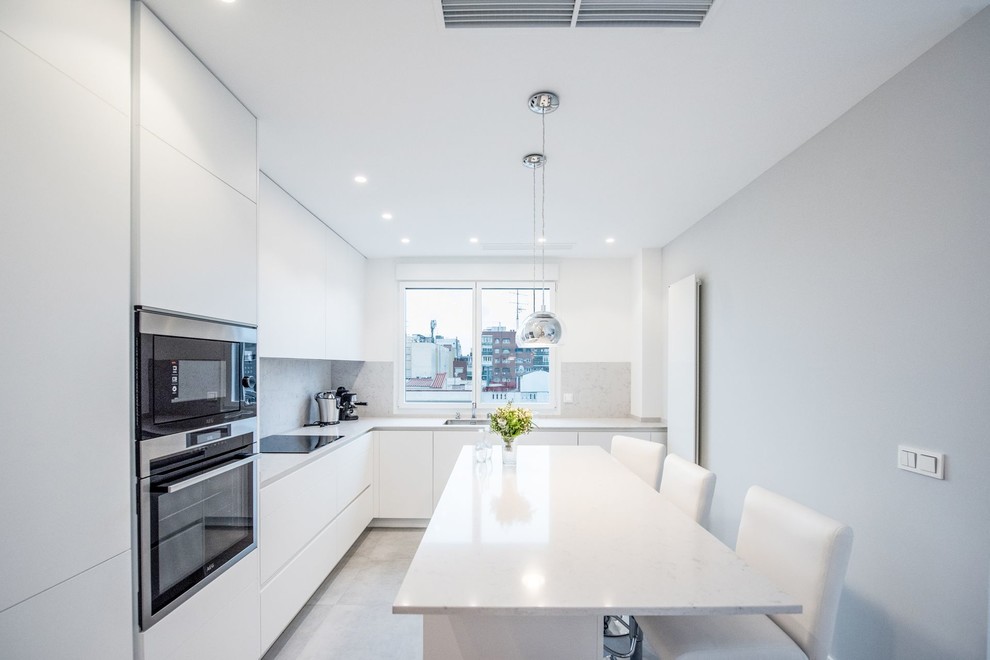 Modern inredning av ett mellanstort grå grått kök, med en nedsänkt diskho, släta luckor, vita skåp, bänkskiva i kvarts, grått stänkskydd, rostfria vitvaror, klinkergolv i keramik, en köksö och grått golv