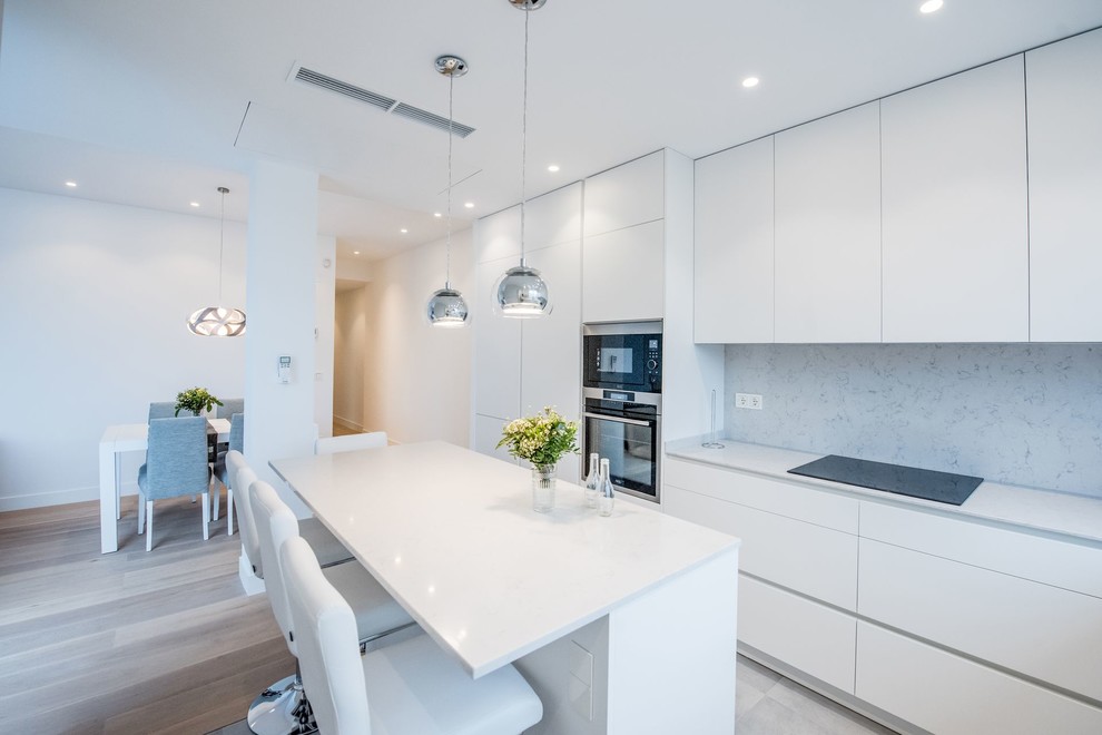 Medium sized modern l-shaped open plan kitchen in Madrid with a built-in sink, flat-panel cabinets, white cabinets, engineered stone countertops, grey splashback, stainless steel appliances, ceramic flooring, an island, grey floors and grey worktops.
