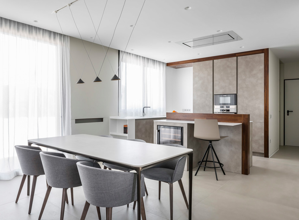 Idée de décoration pour une cuisine américaine minimaliste en L avec un placard à porte plane, des portes de placard beiges, un sol beige, un plan de travail blanc et 2 îlots.