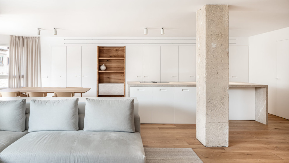 Ejemplo de cocina minimalista abierta con armarios con paneles lisos, puertas de armario blancas, suelo de madera en tonos medios, una isla, suelo marrón y encimeras grises