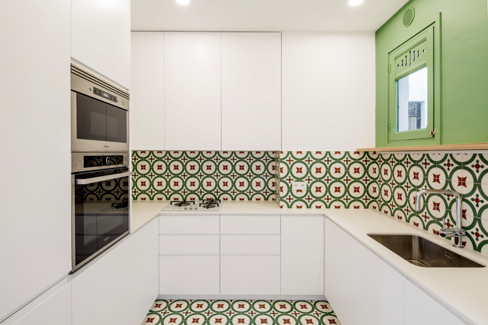 Exempel på ett avskilt, litet eklektiskt vit vitt u-kök, med en undermonterad diskho, släta luckor, vita skåp, kaklad bänkskiva, flerfärgad stänkskydd, stänkskydd i cementkakel, rostfria vitvaror, cementgolv och flerfärgat golv