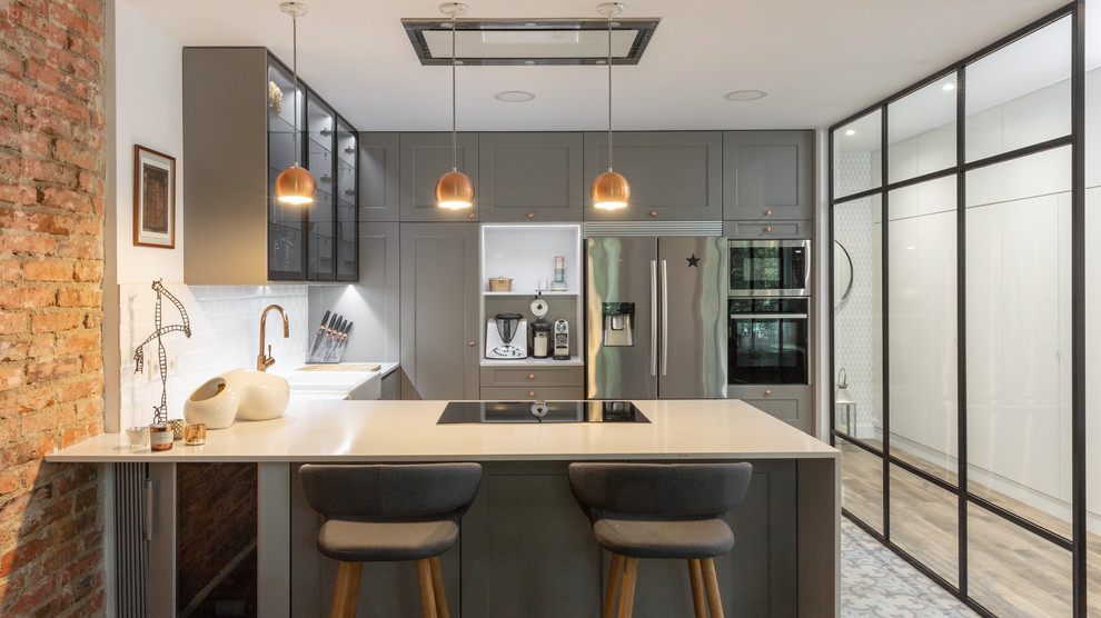 Offene Moderne Küche in U-Form mit Küchengeräten aus Edelstahl, Keramikboden, Halbinsel und weißer Arbeitsplatte in Madrid