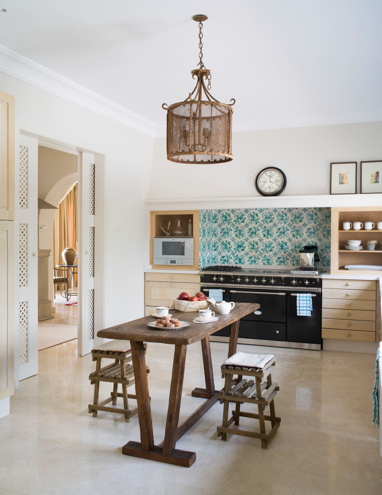 Bild på ett mellanstort medelhavsstil linjärt kök och matrum, med skåp i ljust trä, flerfärgad stänkskydd, svarta vitvaror, släta luckor, bänkskiva i rostfritt stål, stänkskydd i keramik och travertin golv