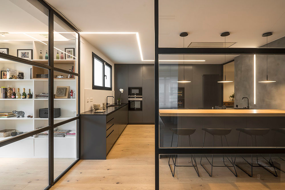 Inspiration for a large contemporary l-shaped open concept kitchen remodel in Barcelona with flat-panel cabinets, black cabinets, white backsplash and a peninsula