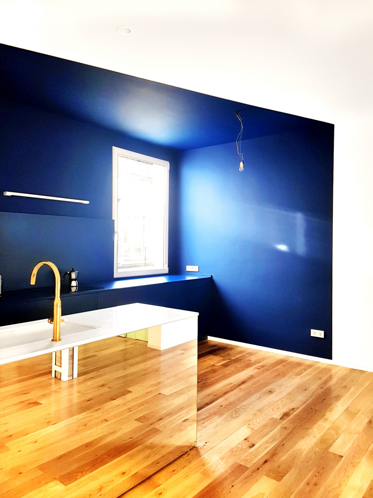Offene, Einzeilige, Mittelgroße Moderne Küche mit Landhausspüle, Schrankfronten im Shaker-Stil, blauen Schränken, Quarzwerkstein-Arbeitsplatte, Küchenrückwand in Blau, braunem Holzboden, Kücheninsel und weißer Arbeitsplatte in Madrid