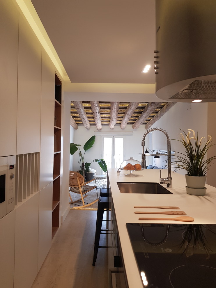 Свежая идея для дизайна: прямая кухня-гостиная в скандинавском стиле с врезной мойкой, плоскими фасадами, белыми фасадами, техникой под мебельный фасад, светлым паркетным полом и островом - отличное фото интерьера