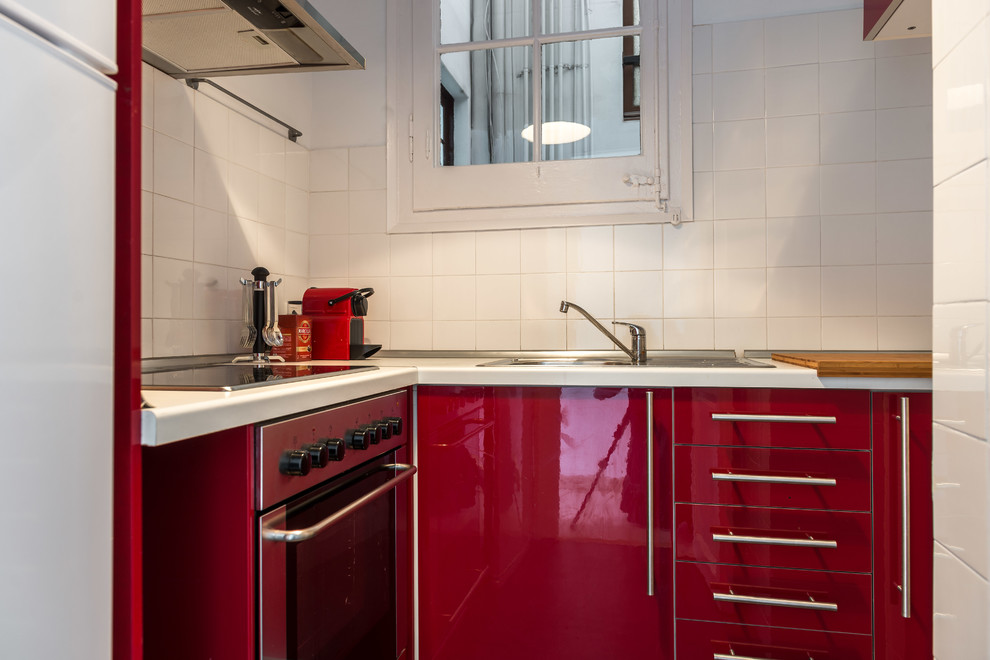 Esempio di una piccola cucina a L classica chiusa con ante lisce, ante rosse, paraspruzzi bianco, paraspruzzi con piastrelle in ceramica, elettrodomestici in acciaio inossidabile e nessuna isola
