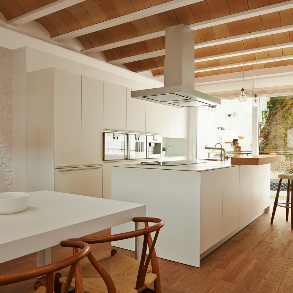 Cette photo montre une grande cuisine ouverte méditerranéenne avec un sol en bois brun, îlot et un sol marron.