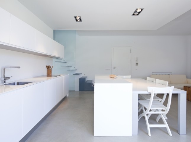 Modelo de cocina lineal contemporánea grande abierta con fregadero bajoencimera, armarios con paneles lisos, puertas de armario blancas, salpicadero blanco y una isla