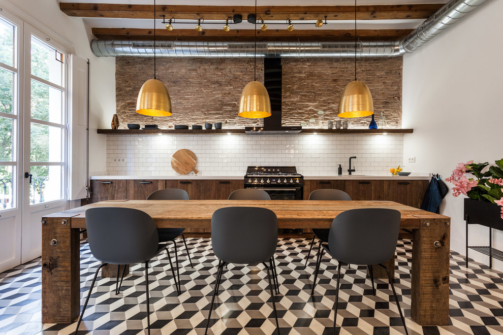 Inspiration for an industrial single-wall kitchen/diner in Barcelona with flat-panel cabinets, dark wood cabinets, white splashback, metro tiled splashback, black appliances and multi-coloured floors.