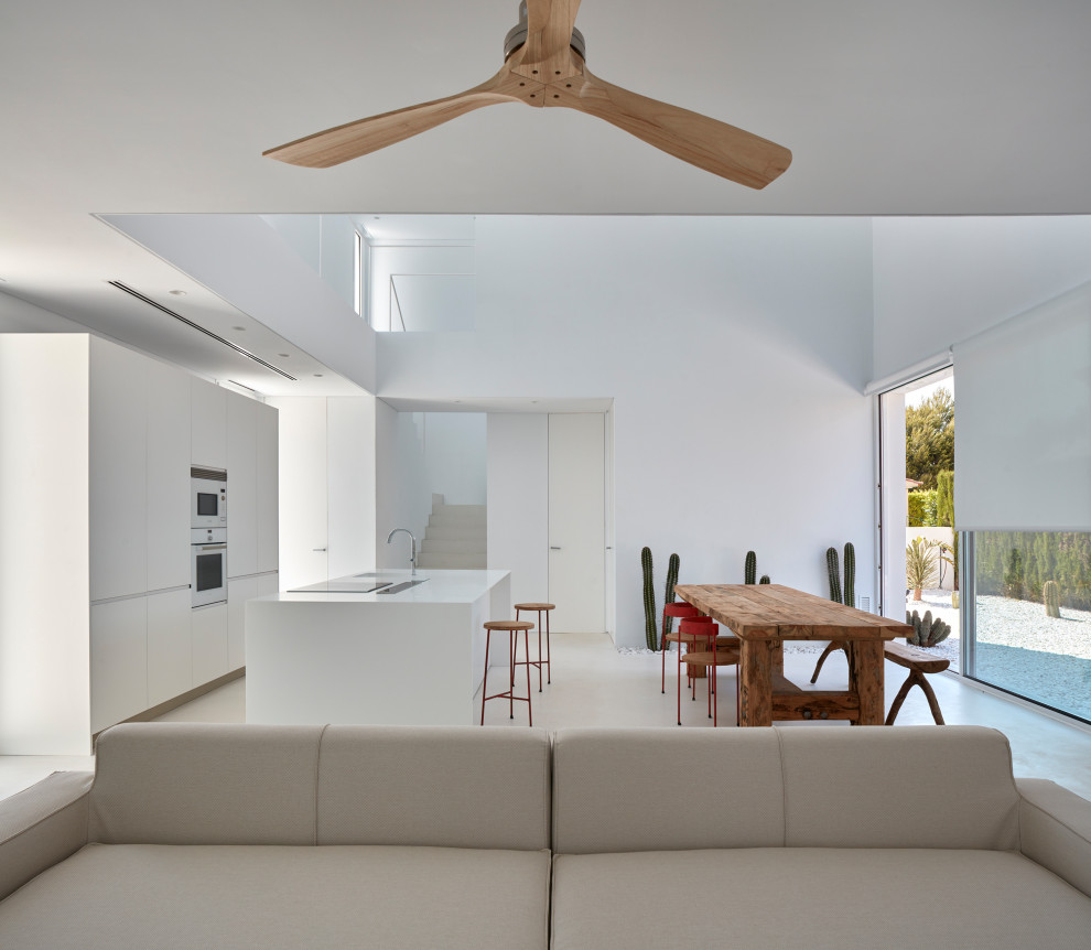Foto di una cucina minimalista con ante lisce, ante bianche, elettrodomestici bianchi, pavimento in cemento, pavimento bianco e top bianco