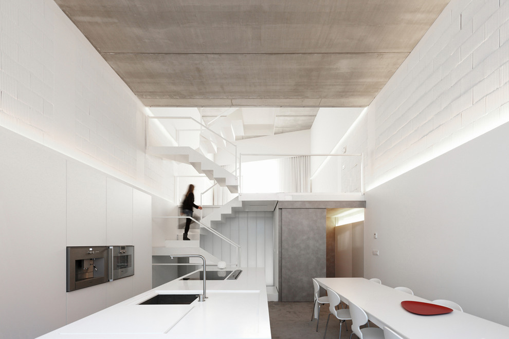 Esempio di una cucina contemporanea di medie dimensioni con lavello sottopiano, ante bianche, top in superficie solida, elettrodomestici in acciaio inossidabile e pavimento in cemento