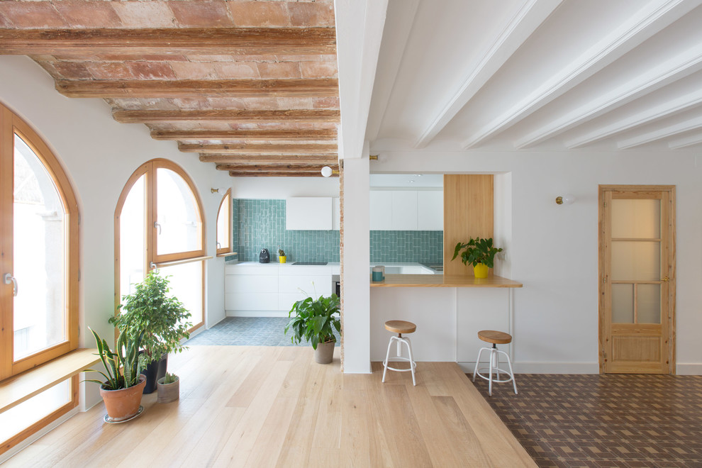 Kleine Mediterrane Wohnküche in U-Form mit flächenbündigen Schrankfronten, weißen Schränken, Küchenrückwand in Blau, Halbinsel, Rückwand aus Keramikfliesen und Keramikboden in Barcelona