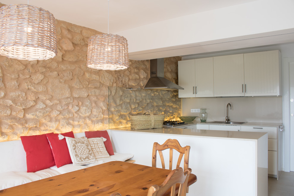 バレンシアにある地中海スタイルのおしゃれなキッチン (ドロップインシンク、フラットパネル扉のキャビネット、白いキャビネット、ベージュキッチンパネル、ガラス板のキッチンパネル、ベージュのキッチンカウンター) の写真