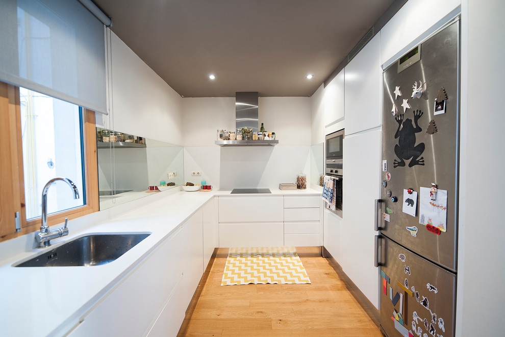 Idéer för att renovera ett avskilt, mellanstort funkis u-kök, med en undermonterad diskho, vita skåp, rostfria vitvaror och släta luckor