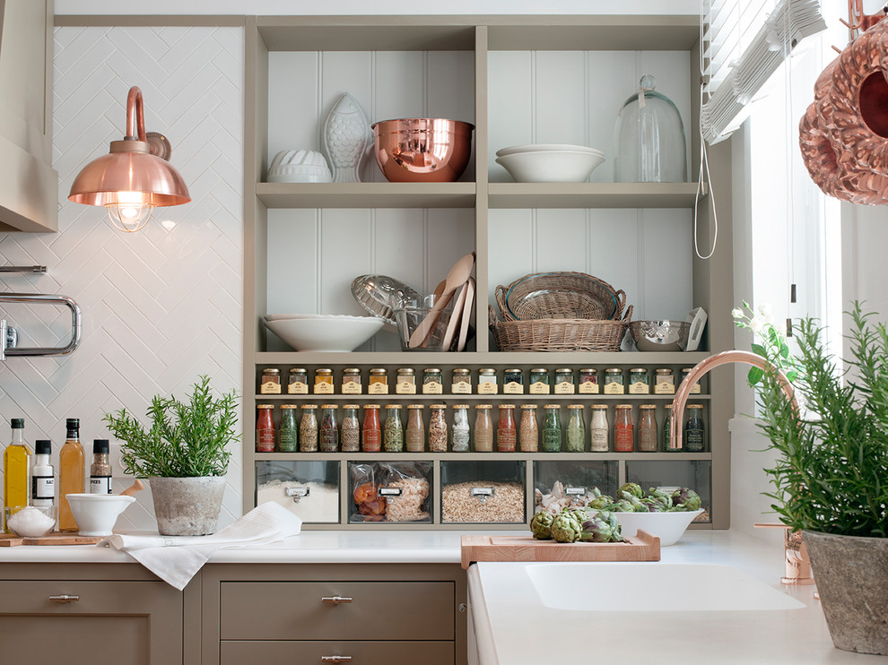 Bild på ett vintage kök och matrum, med en integrerad diskho, beige skåp, bänkskiva i kvarts, vitt stänkskydd, stänkskydd i keramik, rostfria vitvaror, ljust trägolv, en köksö och brunt golv