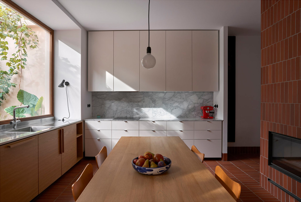 Immagine di una cucina mediterranea con lavello sottopiano, ante lisce, ante beige, paraspruzzi grigio, nessuna isola, pavimento rosso e top grigio
