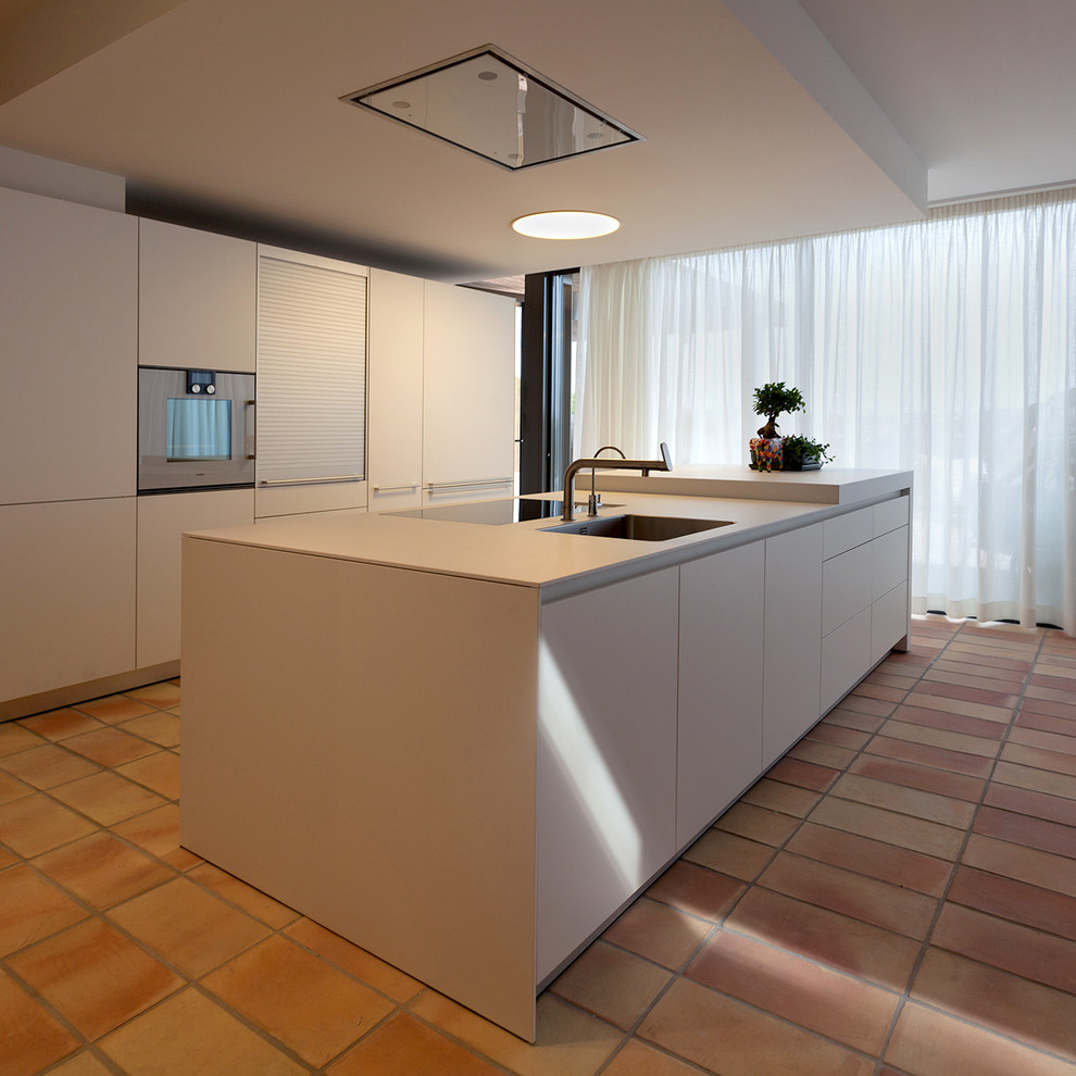 Diseño de cocina lineal actual abierta con armarios con paneles lisos, puertas de armario blancas, una isla y encimeras blancas
