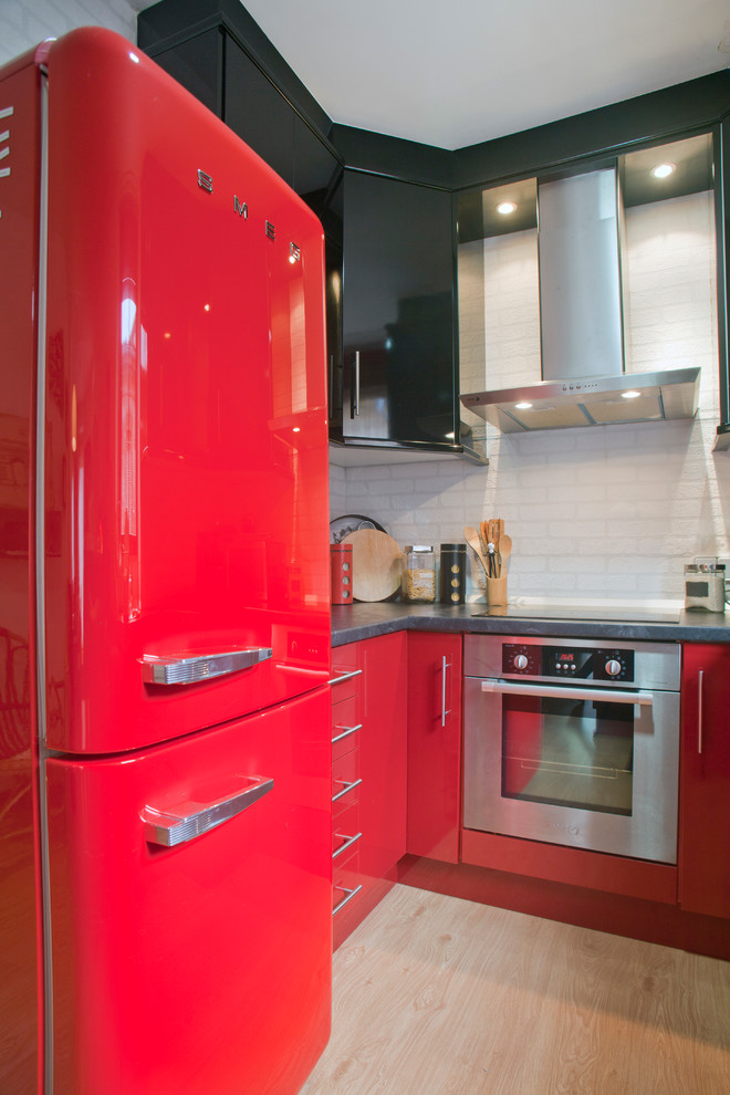 バレンシアにあるお手頃価格の中くらいなコンテンポラリースタイルのおしゃれなキッチン (フラットパネル扉のキャビネット、赤いキャビネット、白いキッチンパネル、カラー調理設備、淡色無垢フローリング、アイランドなし) の写真