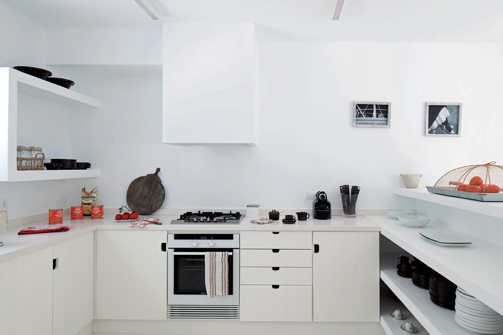 Offene, Mittelgroße Mediterrane Küche ohne Insel in U-Form mit profilierten Schrankfronten, weißen Schränken, Küchenrückwand in Weiß und Küchengeräten aus Edelstahl in Sonstige