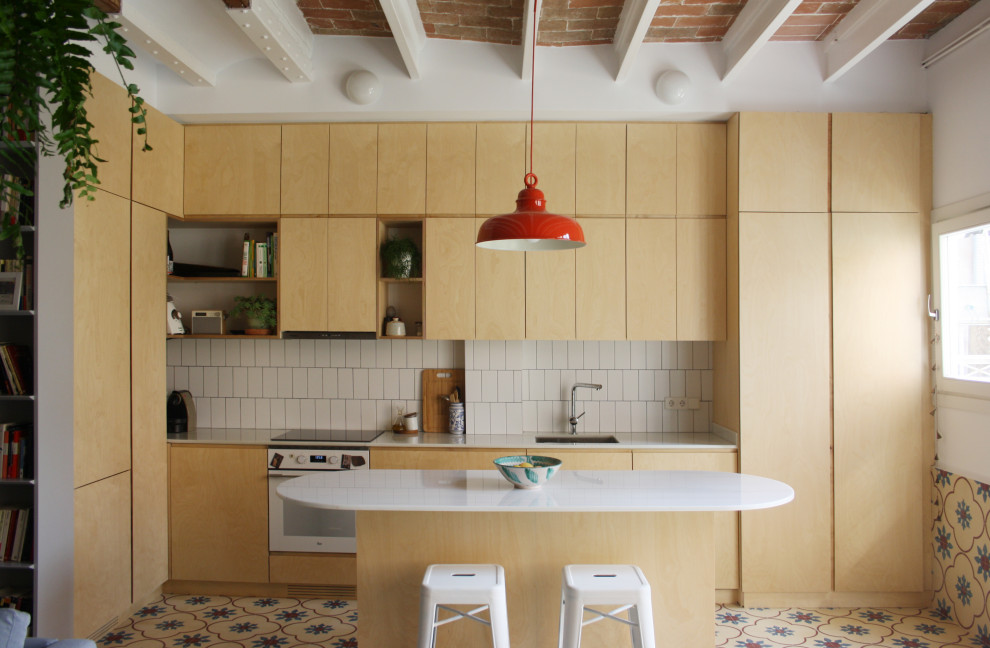 Immagine di un cucina con isola centrale mediterraneo con lavello sottopiano, ante lisce, ante in legno chiaro, paraspruzzi bianco, elettrodomestici bianchi, pavimento multicolore e top bianco
