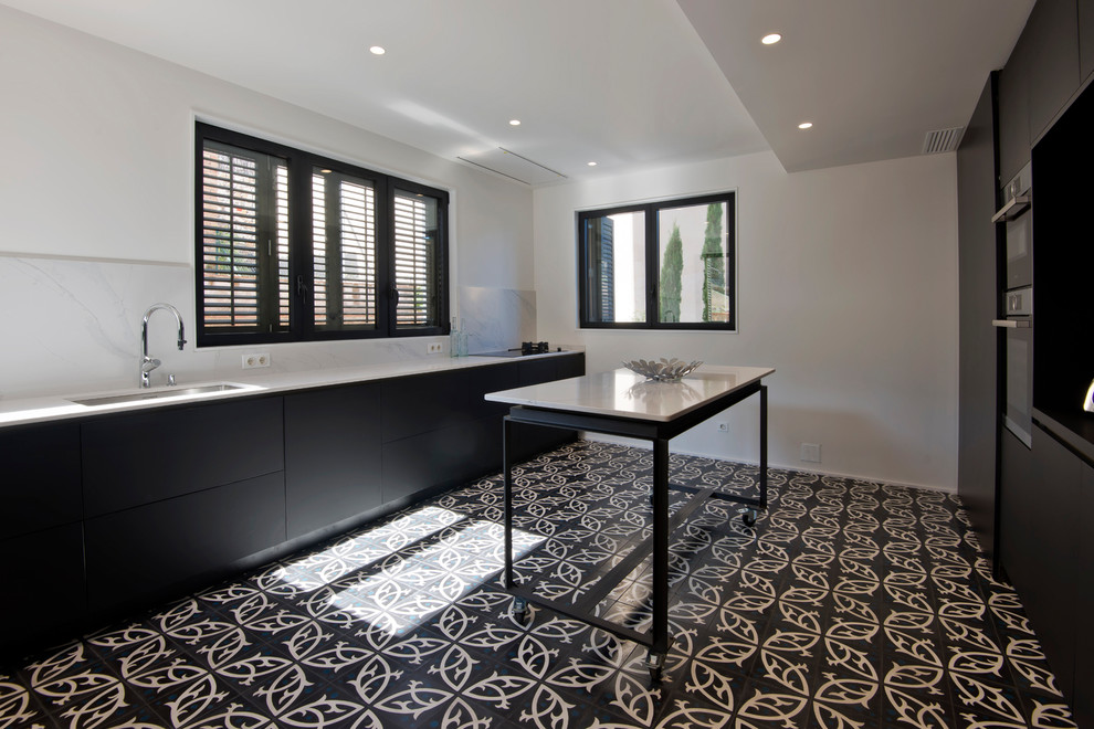 This is an example of a medium sized mediterranean single-wall enclosed kitchen in Barcelona with flat-panel cabinets, black cabinets, marble worktops, white splashback, ceramic flooring, no island and black floors.