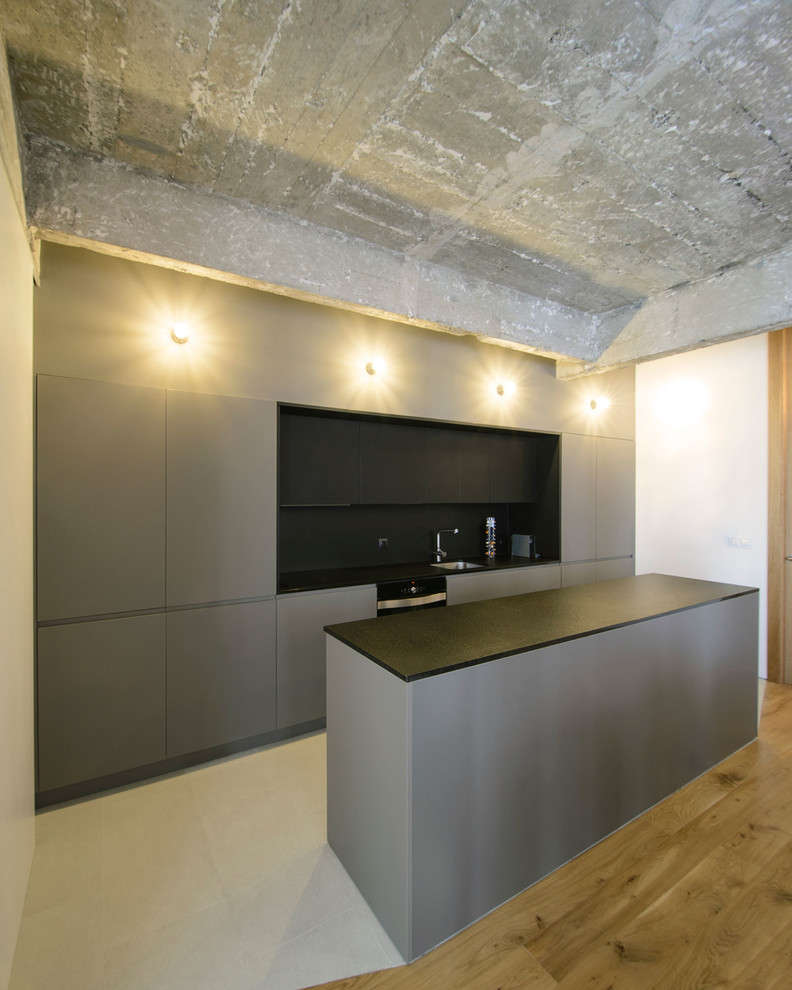 Design ideas for an urban single-wall kitchen in Bilbao with a submerged sink, grey cabinets, black splashback, porcelain flooring and an island.