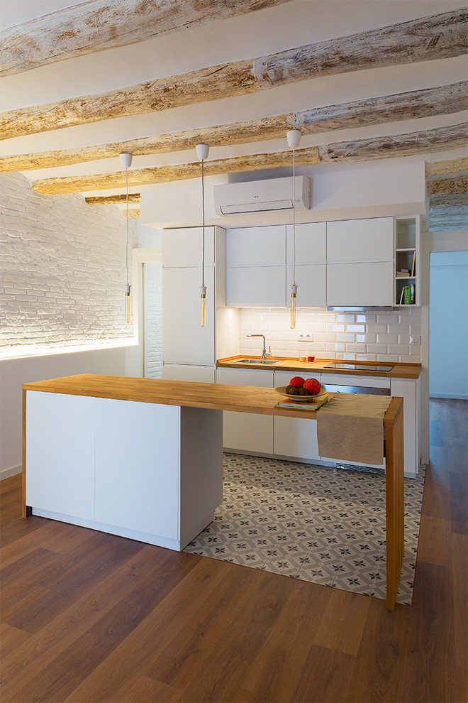 バルセロナにある低価格の小さなコンテンポラリースタイルのおしゃれなキッチン (シングルシンク、フラットパネル扉のキャビネット、白いキャビネット、木材カウンター、白いキッチンパネル、サブウェイタイルのキッチンパネル、白い調理設備、無垢フローリング、茶色い床) の写真