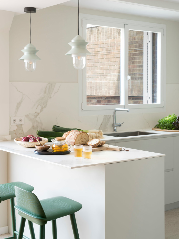 Idéer för att renovera ett mellanstort minimalistiskt grå grått kök, med släta luckor, grå skåp, vitt stänkskydd, integrerade vitvaror, en halv köksö och grått golv