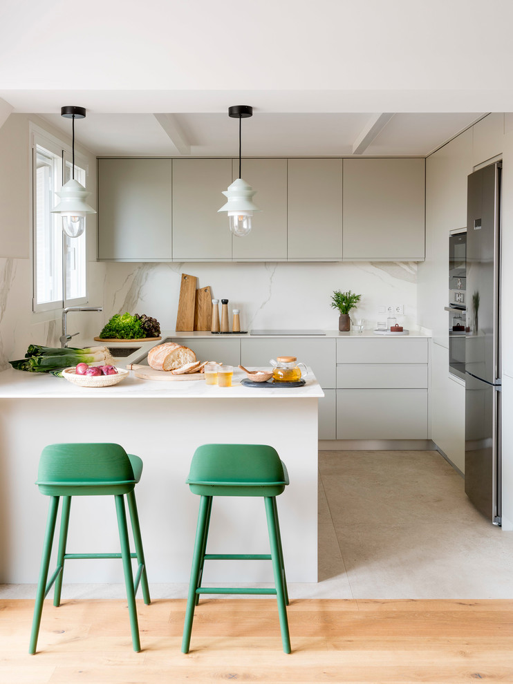 Kitchen - mid-sized scandinavian u-shaped beige floor kitchen idea in Barcelona with flat-panel cabinets, gray cabinets, white backsplash, a peninsula, a single-bowl sink, stone slab backsplash, stainless steel appliances and white countertops