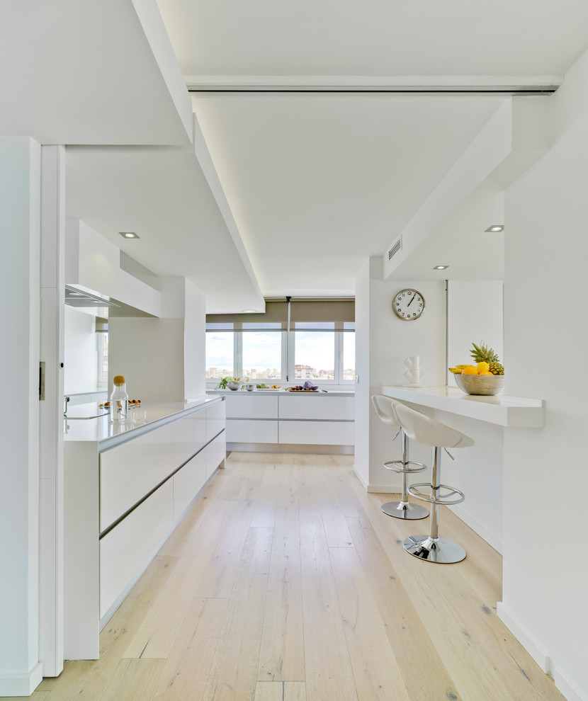 Idéer för stora funkis linjära kök med öppen planlösning, med släta luckor, vita skåp, bänkskiva i kvarts, ljust trägolv och beiget golv