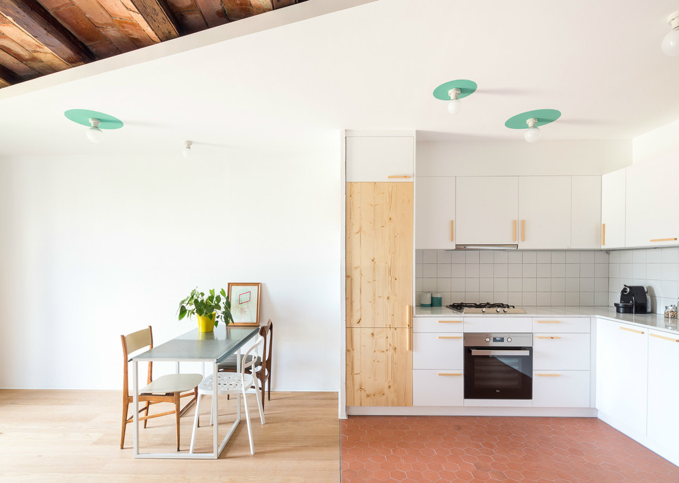 バルセロナにある中くらいな北欧スタイルのおしゃれなキッチン (フラットパネル扉のキャビネット、白いキャビネット、白いキッチンパネル、黒い調理設備、レンガの床、アイランドなし、セラミックタイルのキッチンパネル) の写真