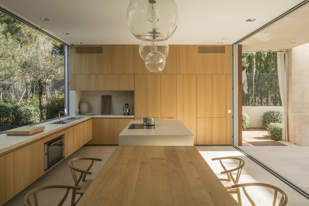 Imagen de cocinas en L minimalista con armarios con paneles lisos, puertas de armario de madera clara, una isla y suelo beige