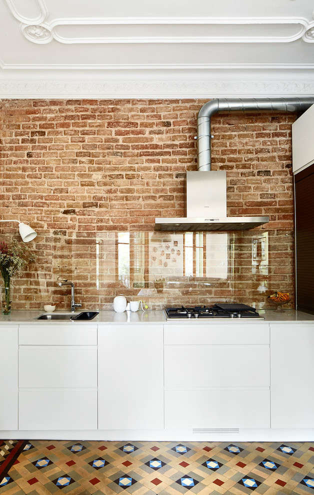 Foto di una cucina minimal con lavello a vasca singola, ante lisce, ante bianche e paraspruzzi con lastra di vetro