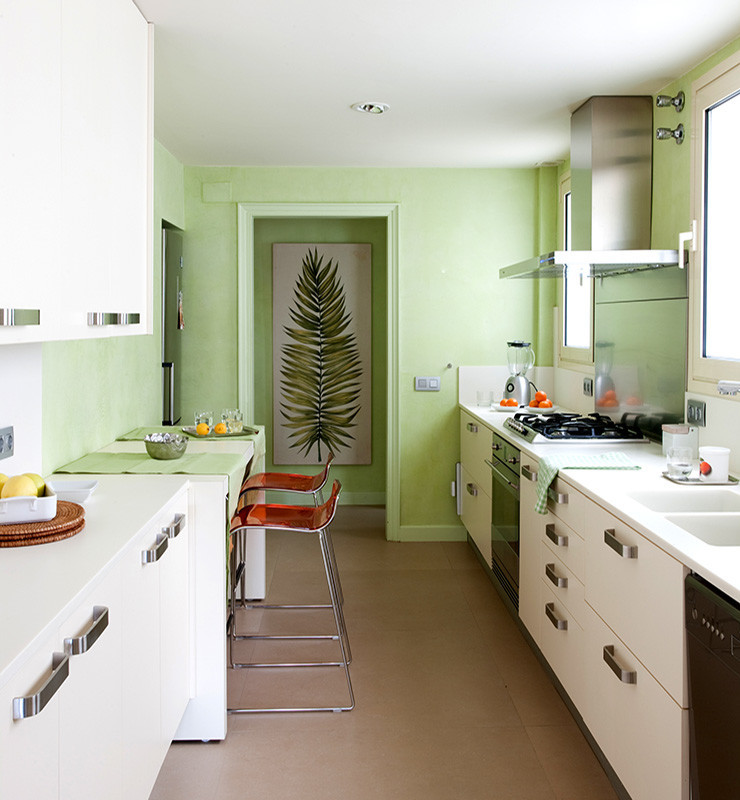 Foto di una cucina parallela tropicale chiusa e di medie dimensioni con lavello a doppia vasca, ante lisce, ante bianche, elettrodomestici neri, pavimento con piastrelle in ceramica e nessuna isola