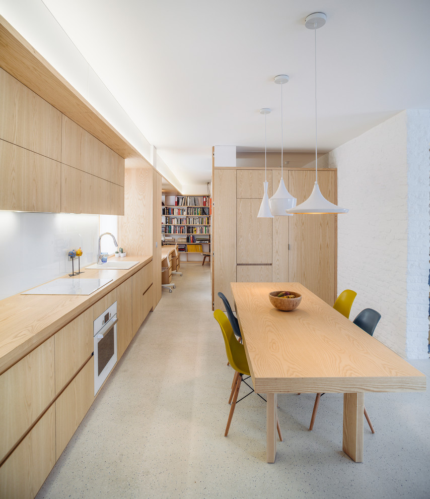 Imagen de cocina comedor lineal escandinava de tamaño medio sin isla con fregadero bajoencimera, armarios con paneles lisos, puertas de armario de madera clara, encimera de madera, salpicadero blanco, salpicadero de vidrio templado y electrodomésticos blancos