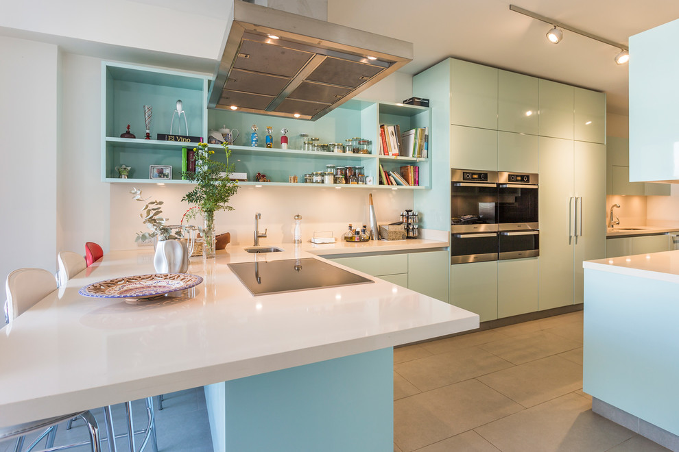 Inspiration for a huge modern l-shaped gray floor kitchen remodel in Madrid with an undermount sink, flat-panel cabinets, blue cabinets, white backsplash, stainless steel appliances, a peninsula and white countertops